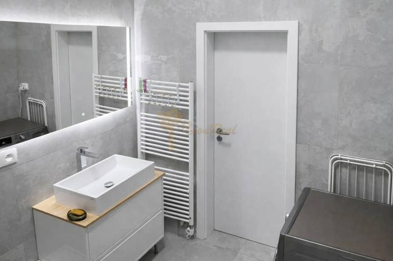 Badezimmer in einer 2-Zimmer-Wohnung mit Waschbecken, Spiegel und Handtuchhalter.