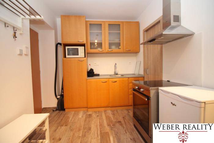 Küche in einer Einzimmerwohnung mit Holzboden, helle Holzschränke.
