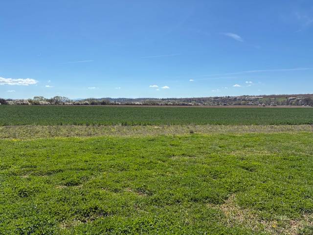 Landwirtschaftliche und forstwirtschaftliche Flächen in Dežerice mit weitläufigen Wiesen und klarem Himmel.