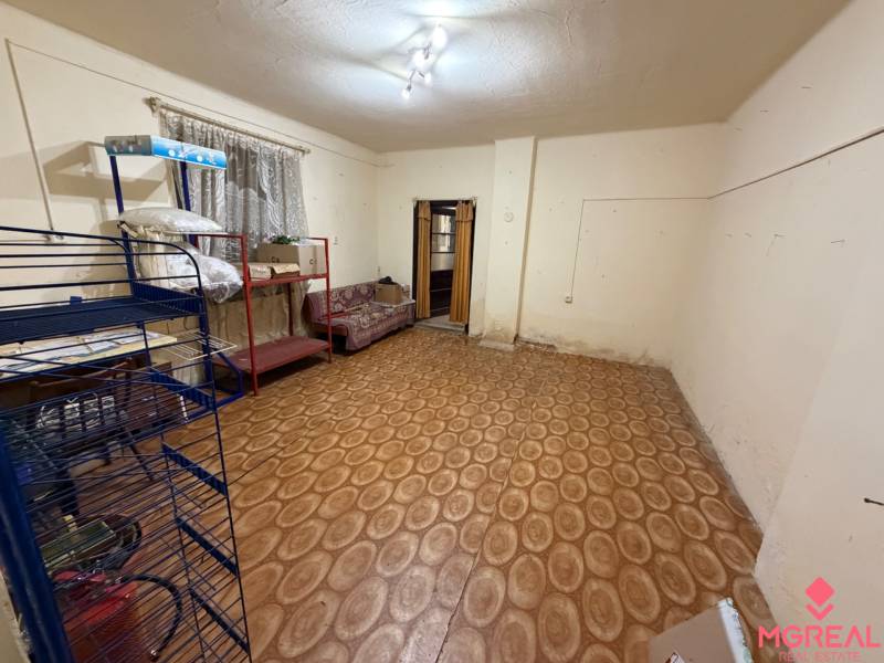 Ein Zimmer in einem Einfamilienhaus mit einem Boden in Holzoptik und einfacher Einrichtung.