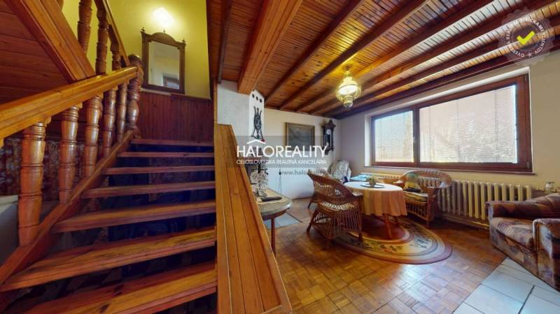 Innenraum eines Einfamilienhauses mit Treppe, Holzboden und Rattanmöbeln.