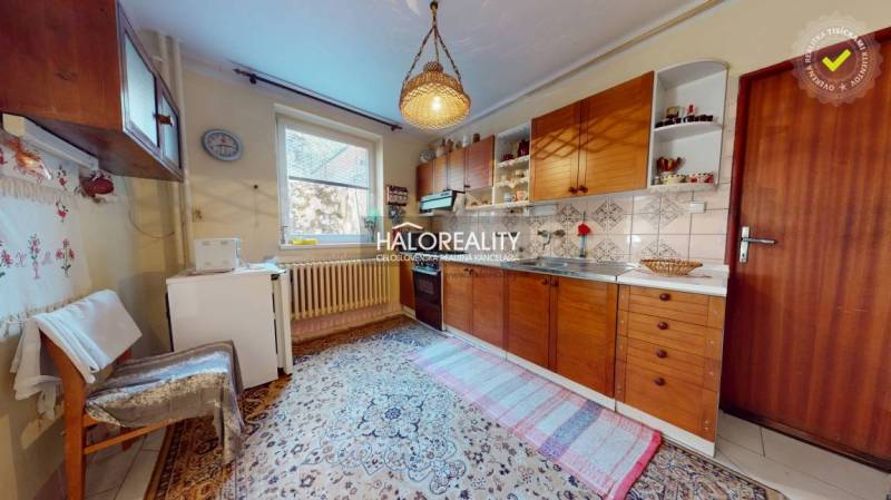 Küche in einem Einfamilienhaus mit Holzschränken, Teppichboden und einer Hängelampe.