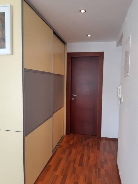 Flur in einer 3-Zimmer-Wohnung mit Holzboden und Einbauschrank.