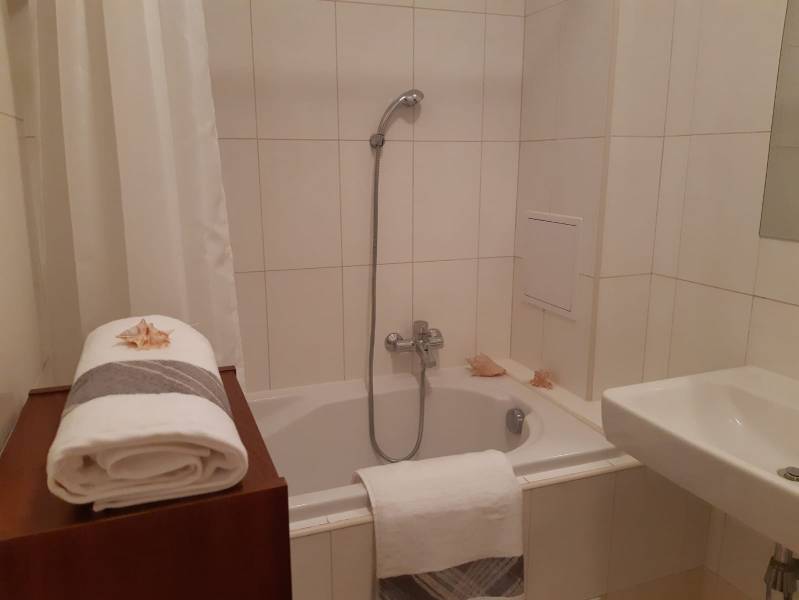 Badezimmer mit Dusche, Badewanne, Waschbecken und weißen Handtüchern, geeignet für eine 3-Zimmer-Wohnung.