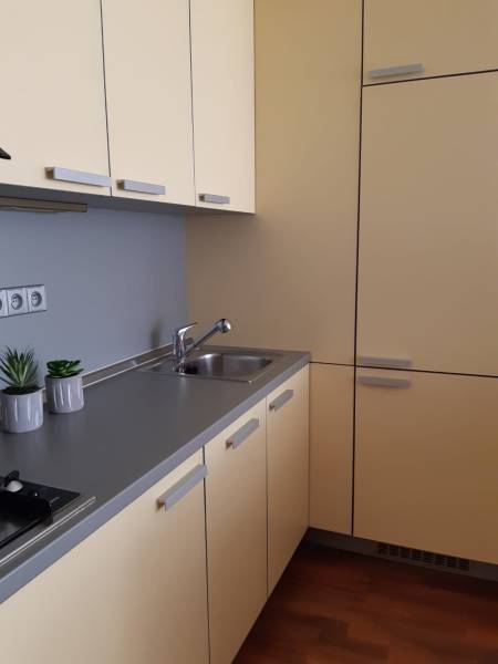 Küche in einer 3-Zimmer-Wohnung mit cremefarbenen Schränken und einem Boden in Holzoptik.