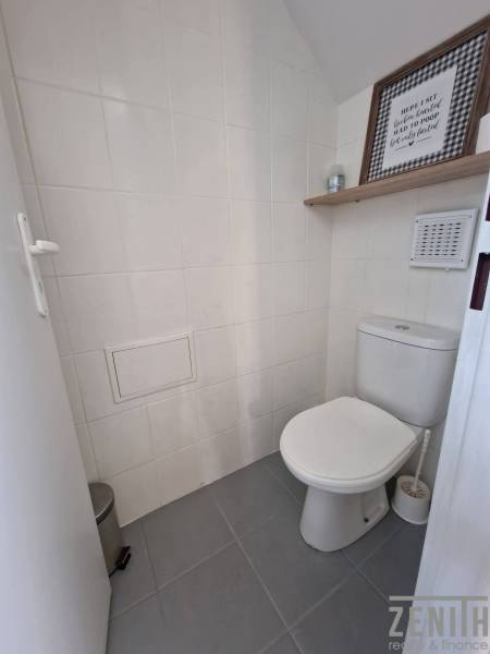 Toilette mit weißen Fliesen und dekorativem Regal in Geschäftsräumen.