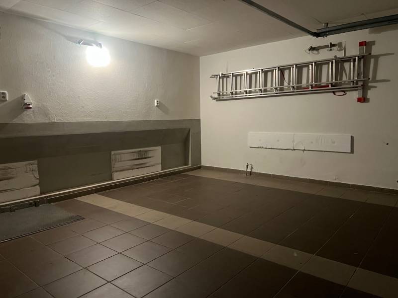 Eine Garage in einem Einfamilienhaus mit Keramikfliesen und einer Leiter an der Wand.