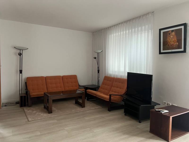 Wohnzimmer in einem Einfamilienhaus mit Holzboden, Sofa und Fernseher.
