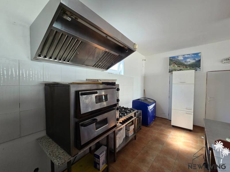 Gastronomiebereiche mit Ofen, Dunstabzugshaube und Kühlschrank, Boden mit Holzdekor.
