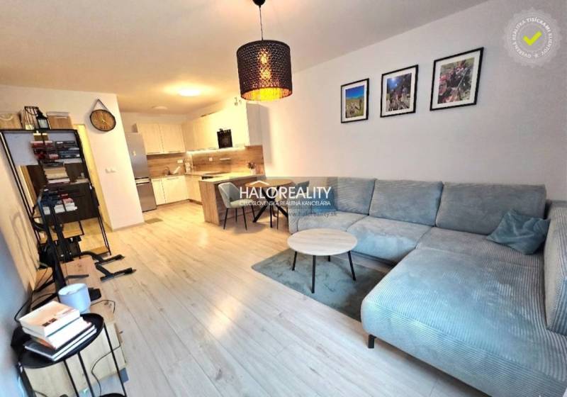 Wohnzimmer mit Ecksofa, Küche und Holzboden in einer 2-Zimmer-Wohnung.