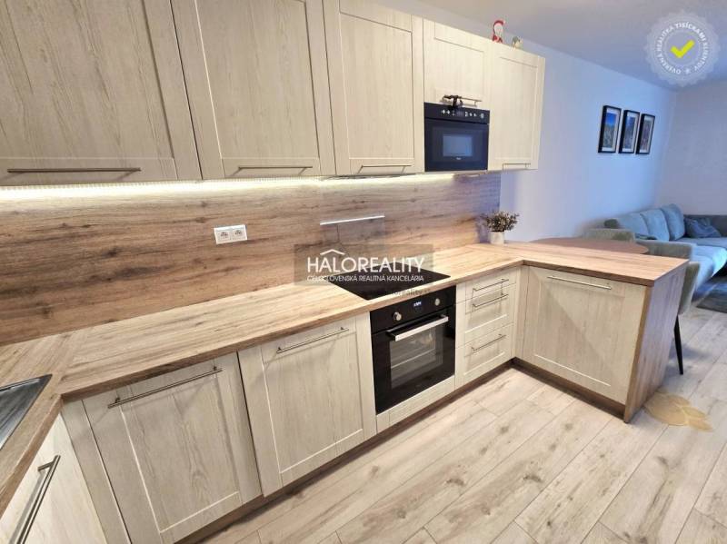 Küche mit Holzboden in einer 2-Zimmer-Wohnung, helle Holzschränke und eingebaute Geräte.