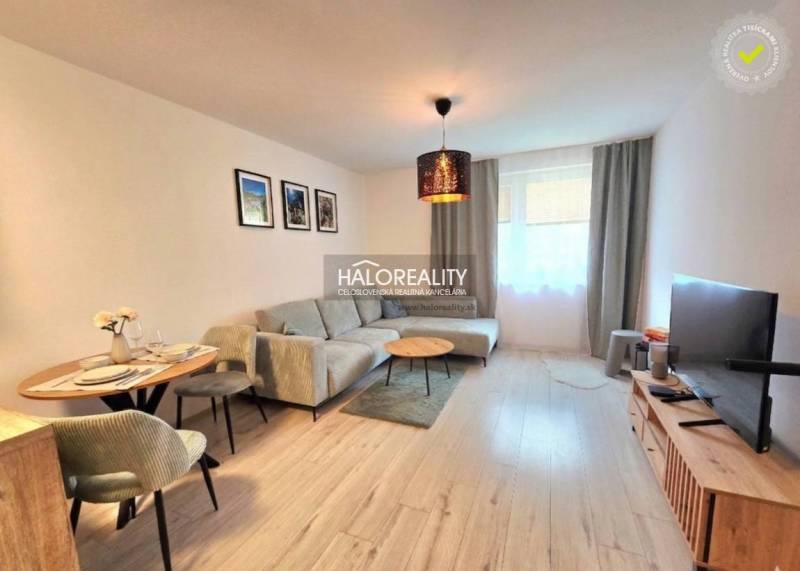 Wohnzimmer in einer 2-Zimmer-Wohnung mit Ecksofa und Fernseher, Boden mit Holzdekor.