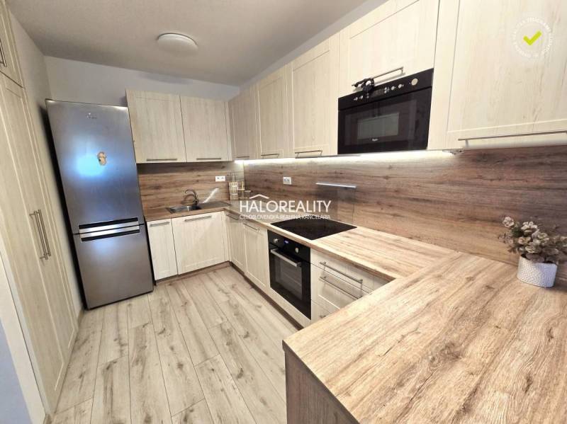 Küche in einer 2-Zimmer-Wohnung mit Holzboden und hellen Möbeln.