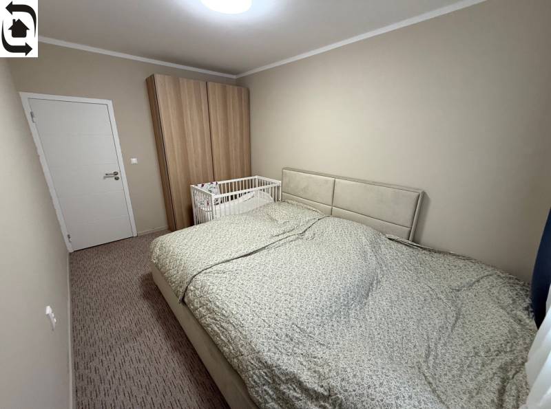 Schlafzimmer mit grauem Bett, Kinderbett und Kleiderschrank in einer 4-Zimmer-Wohnung.
