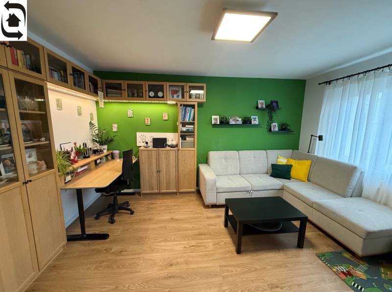 Wohnzimmer mit Sofa, Schreibtisch und Holzboden in einer Vierzimmerwohnung.