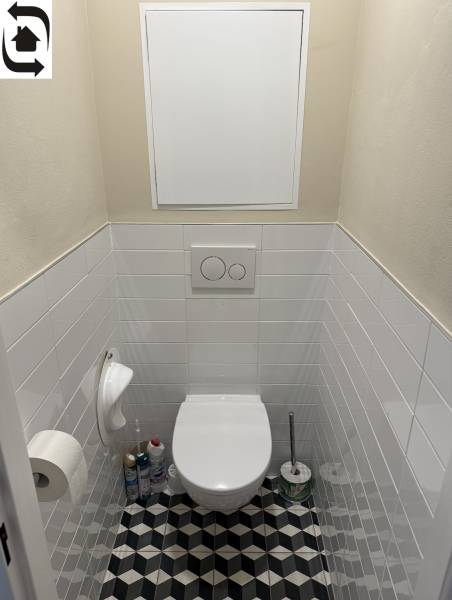 Toilette in einer 4-Zimmer-Wohnung mit geometrischen Fliesen und weißen Kacheln.