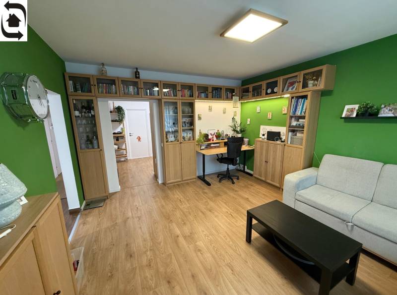 Wohnzimmer in einer Vierzimmerwohnung mit Holzboden und Bücherregal.