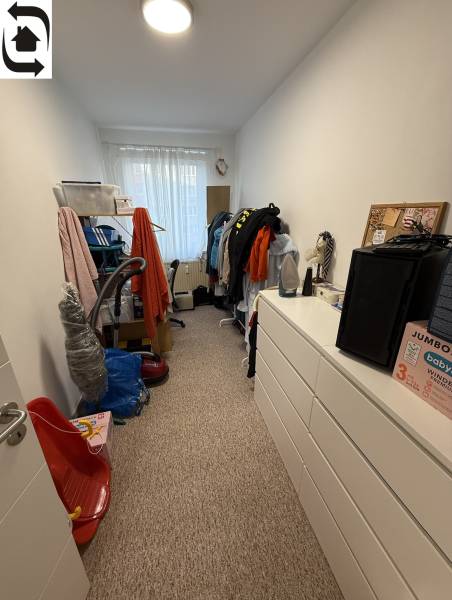 Ein Zimmer mit Schränken und Kleidung in einer 4-Zimmer-Wohnung, dominiert von weißen Wänden und Teppichboden.