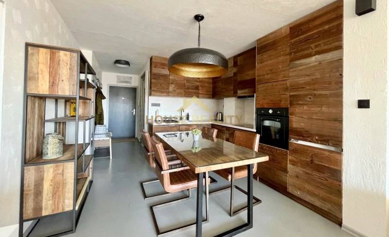 Küche einer 3-Zimmer-Wohnung mit Holzelementen und Esstisch.