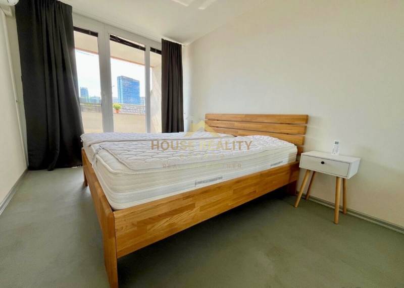 Schlafzimmer mit einem Holzbett, einem Nachttisch und einem Balkon in einer 3-Zimmer-Wohnung.