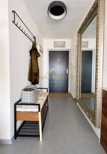 Diele einer 3-Zimmer-Wohnung mit einer Bank, einem Kleiderhaken und einem großen Spiegel an der Wand.