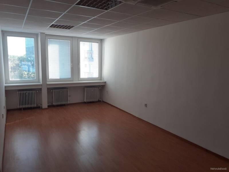Ein leerer Büroraum mit Holzboden und großen Fenstern.
