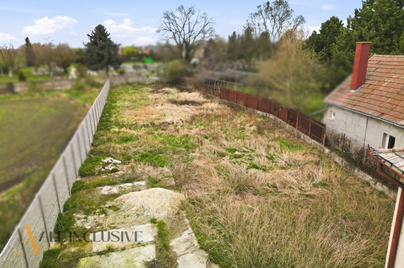 Ein Einfamilienhaus in Michal na Ostrove mit einem weitläufigen, ungepflegten Grundstück und einem Zaun.