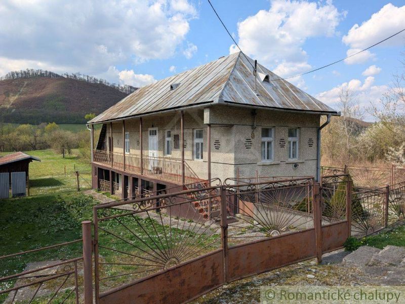 Ein Einfamilienhaus in Zubné mit einem Blechdach, einem Zaun und einer ländlichen Umgebung.