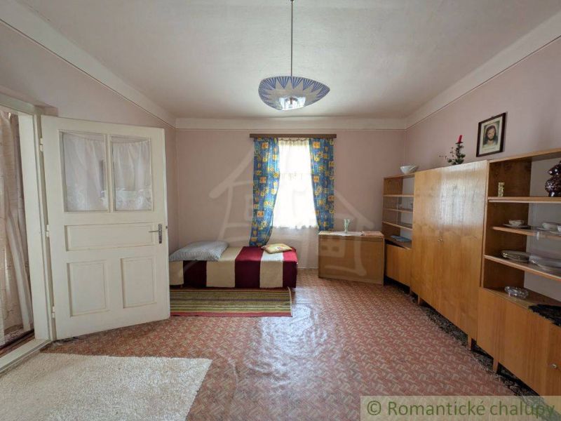 Ein Zimmer mit einfacher Einrichtung, einem Bett und Teppichen in einem Einfamilienhaus.