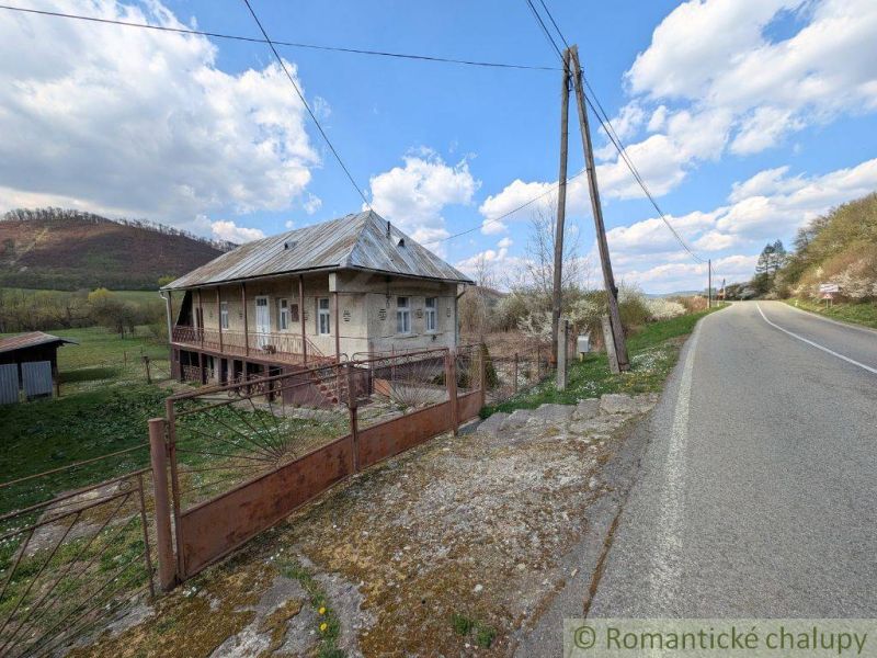 Ein Einfamilienhaus in Zubné mit Veranda, neben der Hauptstraße und in der Nähe einer hügeligen Umgebung.