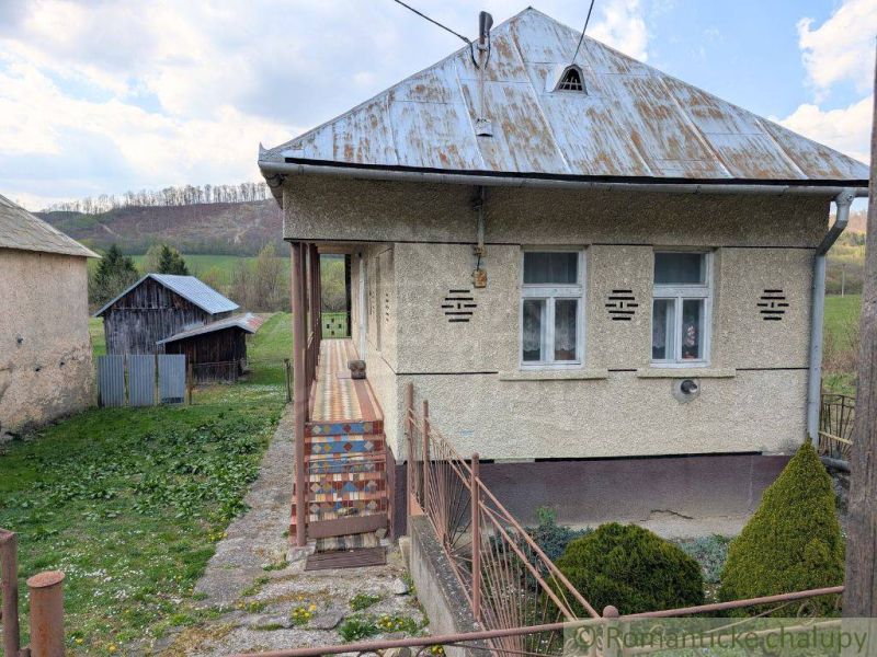 Ein Einfamilienhaus in Zubné mit einem Blechdach, einer Veranda und einem umliegenden Rasen.