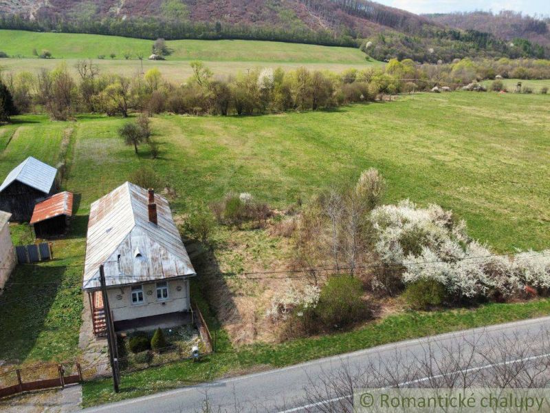 Ein Einfamilienhaus in Zubné, umgeben von Natur und Feldern, mit einem Holzdach.