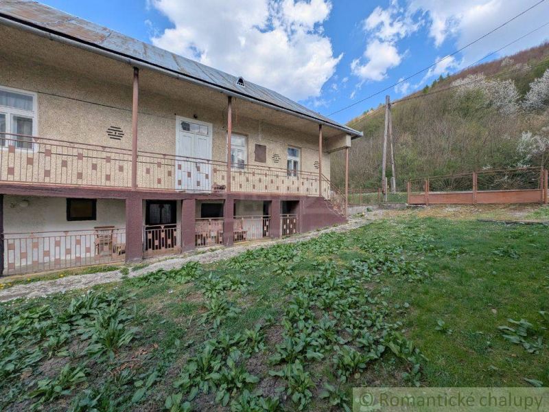 Ein Einfamilienhaus in Zubné mit einer großen Veranda, einem grünen Rasen und einem Hang.