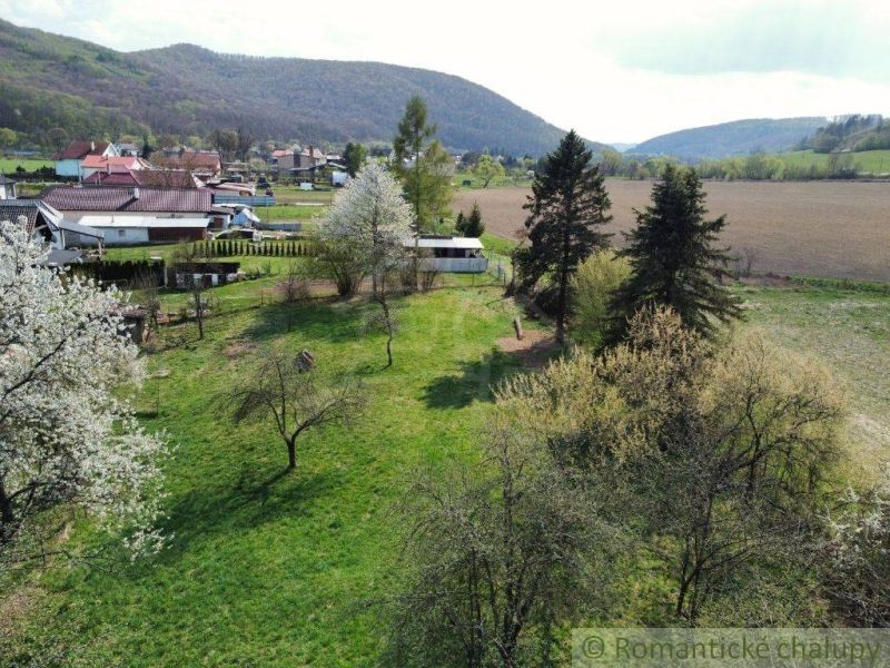 Ein Einfamilienhaus in Zubné mit einem weitläufigen Garten, Bäumen und Blick auf die Hügel.