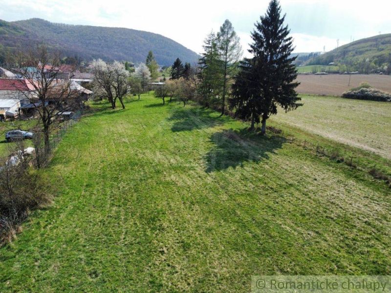 Grünes Grundstück mit Blick auf die Hügel und Bäume in der Nähe von Einfamilienhäusern in Zubné.