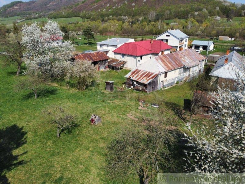 Ein Einfamilienhaus in Zubné mit Garten, Bäumen und älteren Wirtschaftsgebäuden.