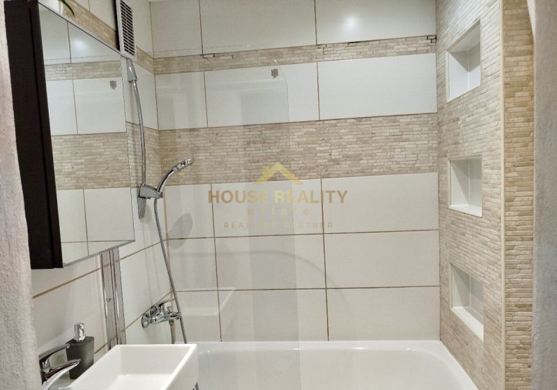 Badezimmer mit Badewanne und Fliesen in einer Einzimmerwohnung.