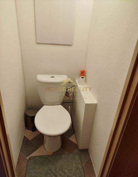 Toilette in einer Einzimmerwohnung mit Fliesen und Hygienebedarf.