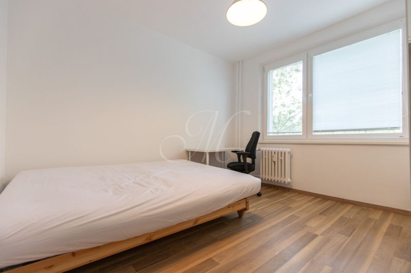 Schlafzimmer mit einem Einzelbett, einem Schreibtisch und einem Boden mit Holzdekor in einer 3-Zimmer-Wohnung.
