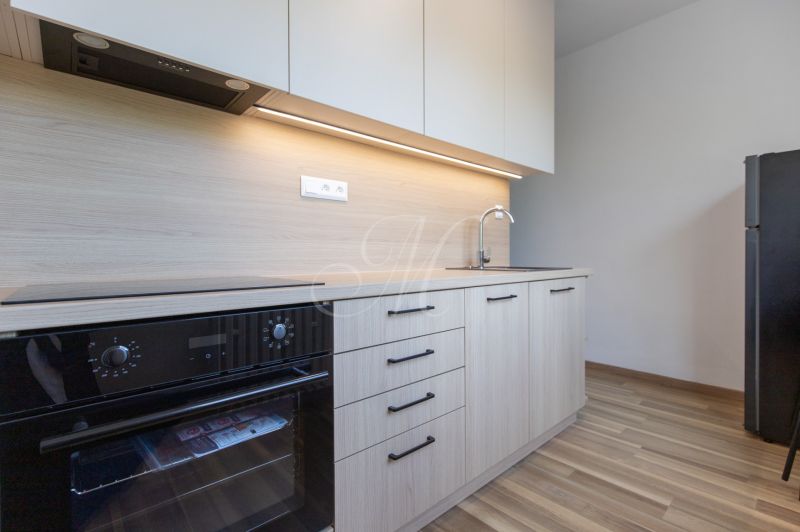 Küche in einer 3-Zimmer-Wohnung mit Holzdekor, eingebautem Ofen und Kühlschrank.
