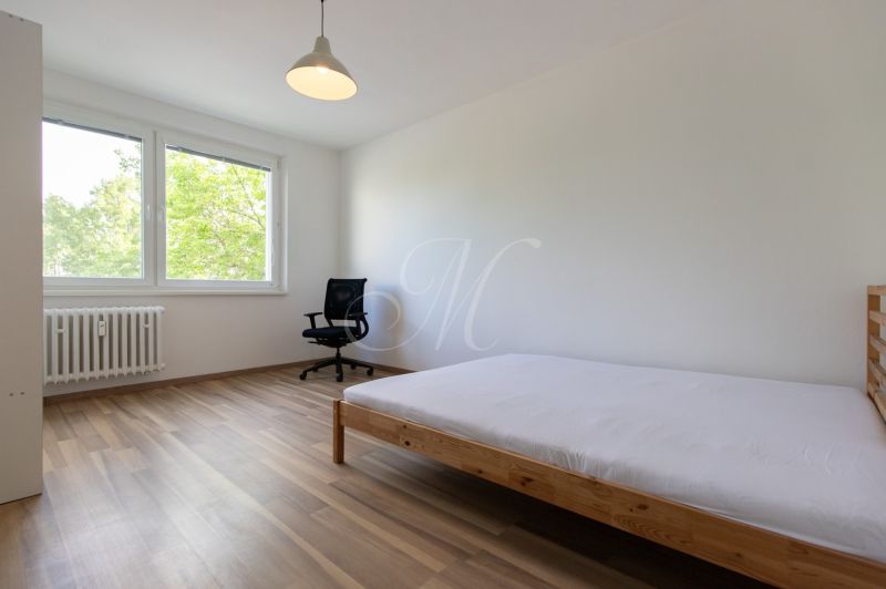 Helles Schlafzimmer in einer 3-Zimmer-Wohnung mit Holzboden und großen Fenstern.