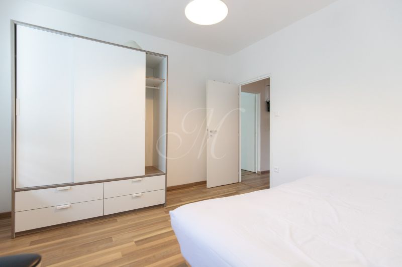Schlafzimmer in einer 3-Zimmer-Wohnung mit weißem Schrank und Boden in Holzoptik.