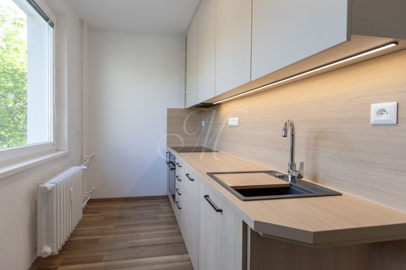 Küche in einer 3-Zimmer-Wohnung mit Holzboden und hellen Schränken.