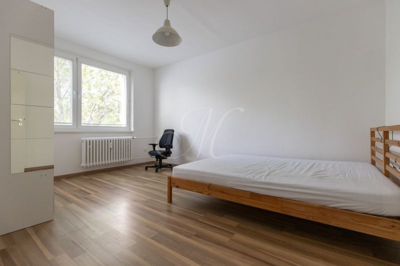 Helles Schlafzimmer mit Bett und Arbeitsstuhl, Boden mit Holzdekor.