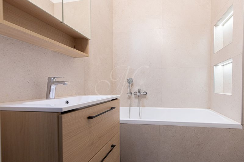 Badezimmer in einer 3-Zimmer-Wohnung mit Badewanne und Schrank mit Holzdekor.