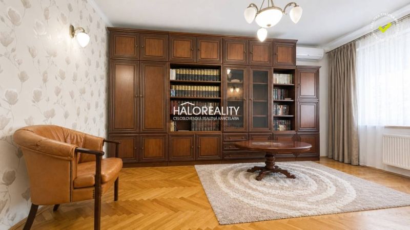 Wohnzimmer in einer 3-Zimmer-Wohnung mit Bibliothek, Sessel und Holzboden.