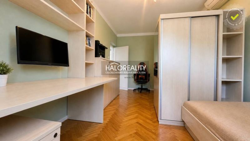 Ein Arbeitszimmer in einer 3-Zimmer-Wohnung mit Regalen, einem Tisch und einem Boden in Holzoptik.