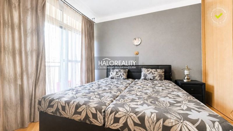 Schlafzimmer mit gemustertem Bettzeug in einer 3-Zimmer-Wohnung, neben dem Schrank und der Lampe.