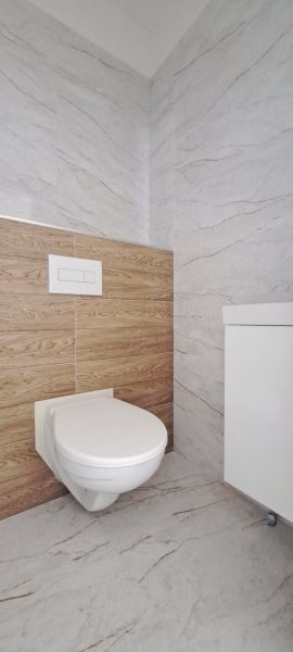 Toilette im Badezimmer eines Einfamilienhauses mit Marmor- und Holzverkleidungen.