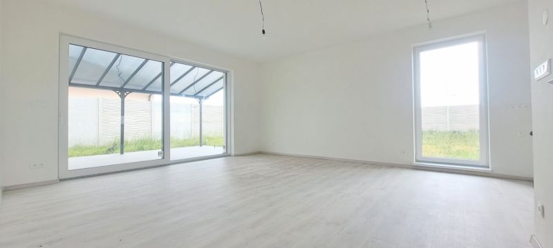 Ein geräumiges Zimmer mit großen Fenstern und einem Holzboden in einem Einfamilienhaus.